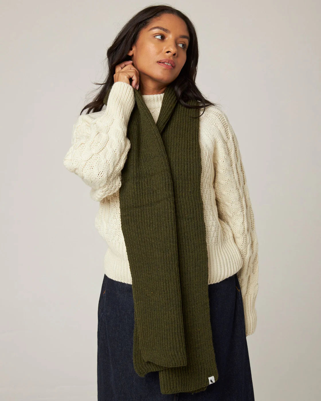 Model wears an olive green ribbed knit merino wool scarf from Peregrine Clothing, filtered on Shop My Palette for the Soft Autumn, Warm Autumn, and Deep Autumn colour seasons.