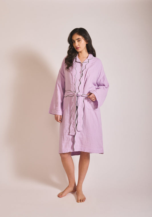 Model wearing a relaxed lavender robe with long sleeves, button front, tie waist, and soft textured cotton fabric.
