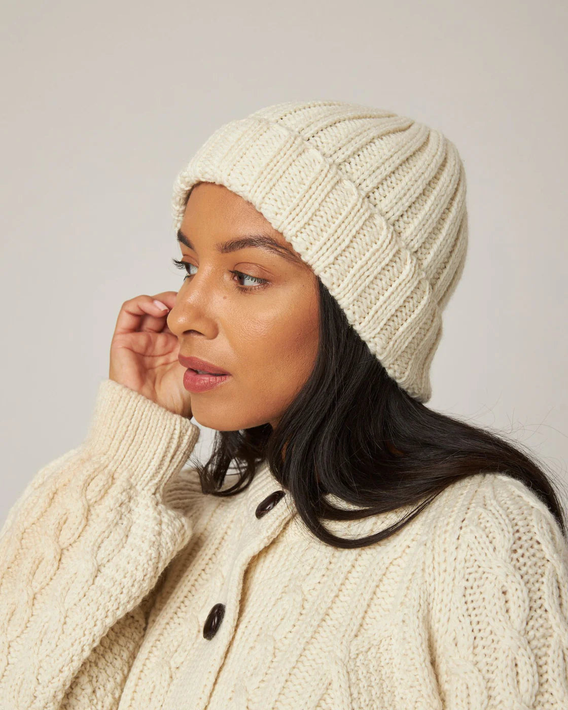 Model wears cream ecru merino wool knitted beanie hat by Peregrine Clothing, filtered for the Light Spring, Clear Spring, and Warm Spring colour seasons by Shop My Palette.