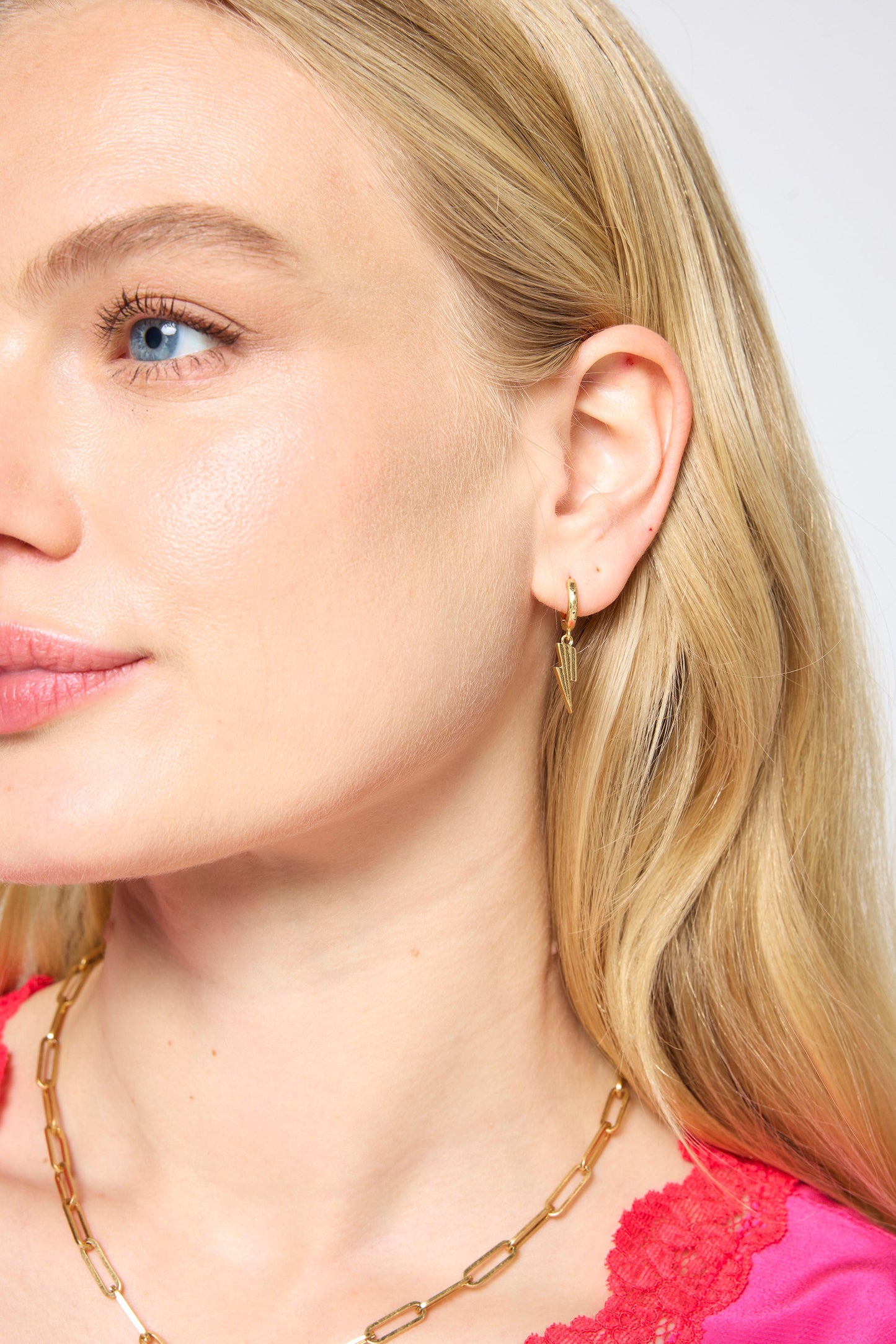 Gold lightning bolt huggie earrings.
