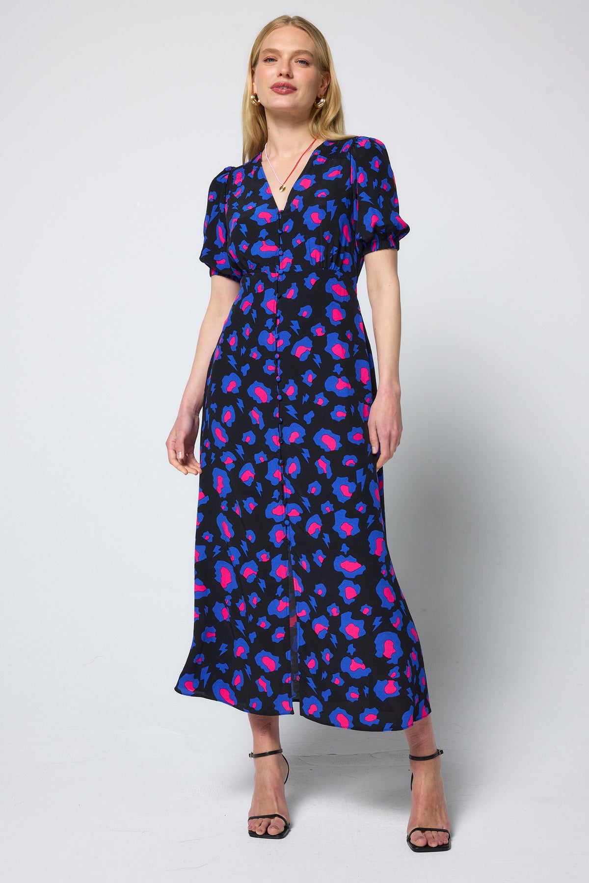 Model wearing black dress with vibrant pink and cobalt animal print pattern.