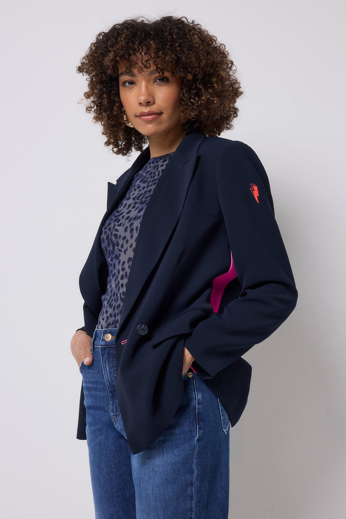 Model wears navy blazer with pink stripe over a leopard-print top and blue jeans.