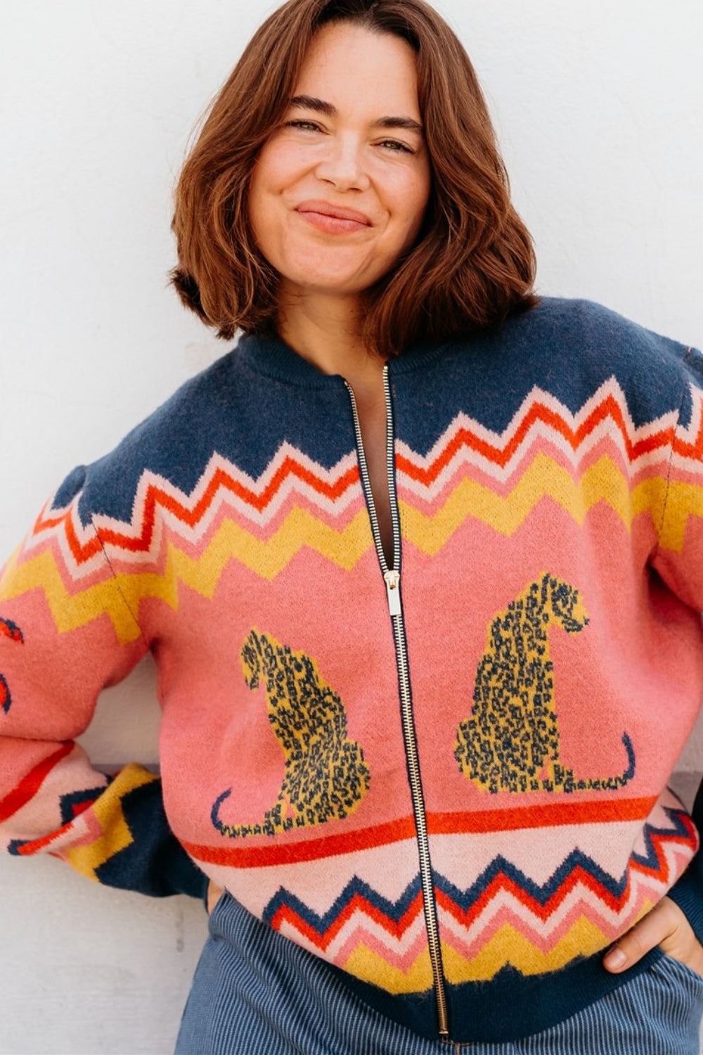 Colourful coral, yellow, navy, and red zigzag pattern knitted cardigan, with leopard motif.