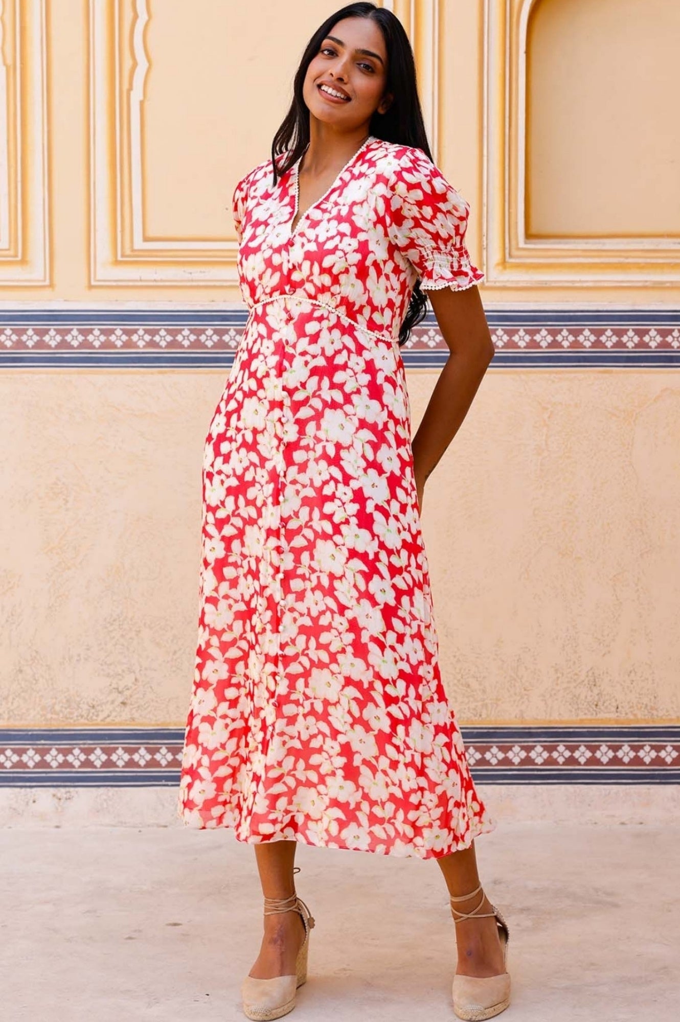 Coral red midi dress with white floral print, V-neckline, short puff sleeves, and fitted waist.