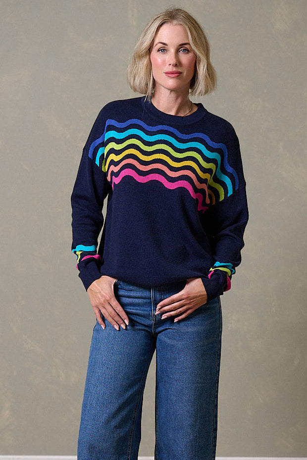 Navy sweater by Sugarhill Brighton with bright rainbow waves across the chest and cuffs.