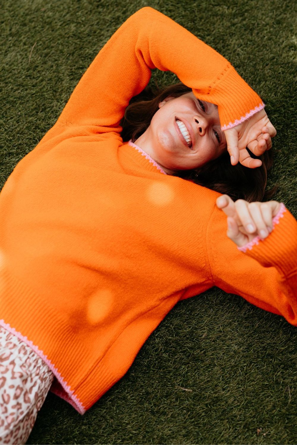 Orange knitted sweater with pink trim at cuffs and neckline.