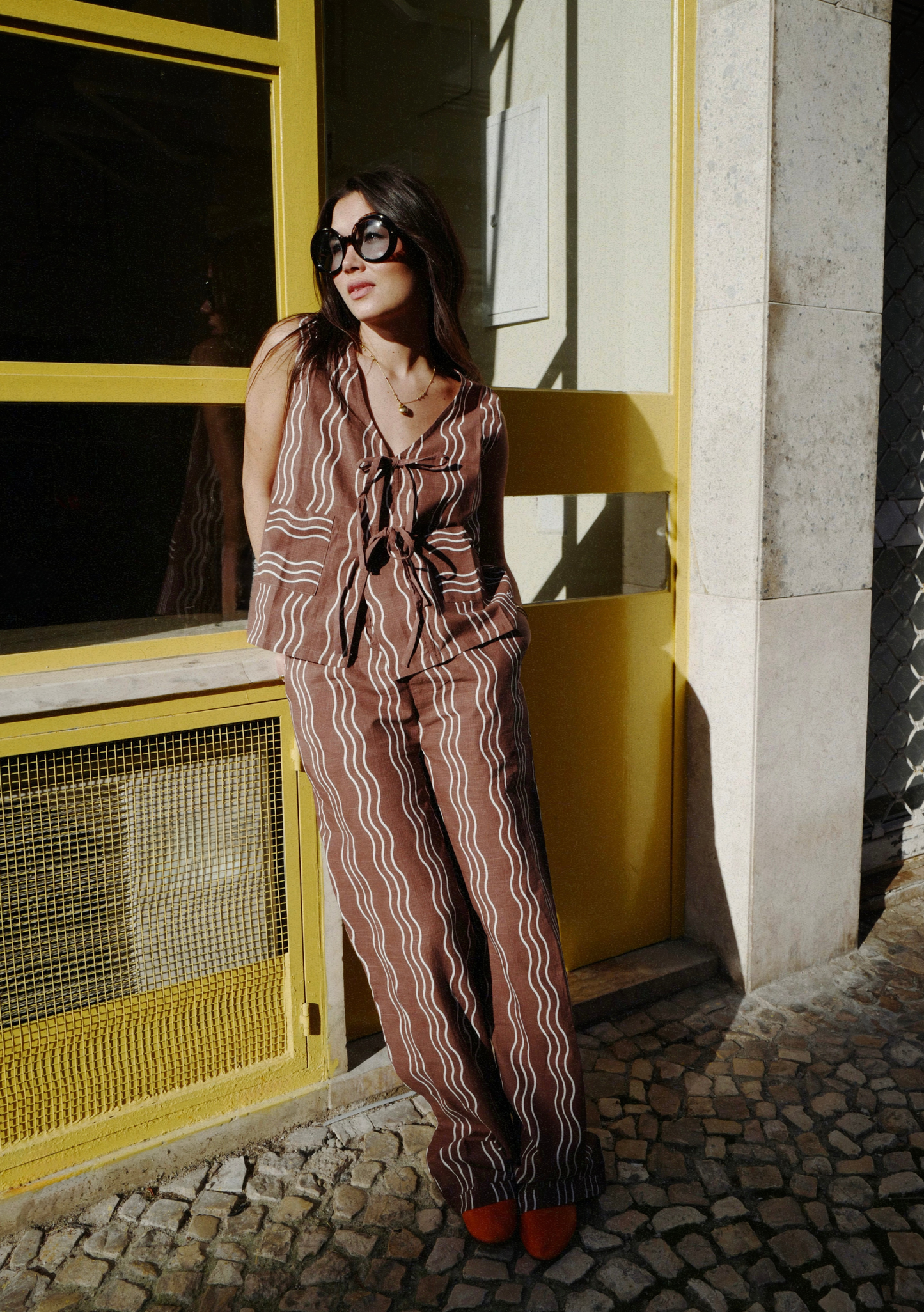 Brown co-ord set with sleeveless tie-front top and matching wide-leg trousers, featuring cream wavy stripe pattern and relaxed fit