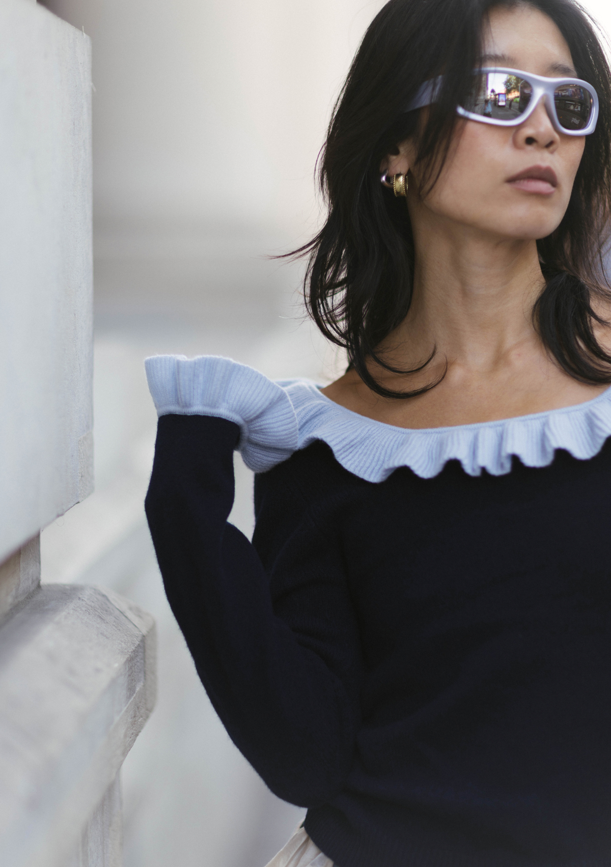 Model wears navy blue merino sweater with pale blue ruffle neck and cuffs.