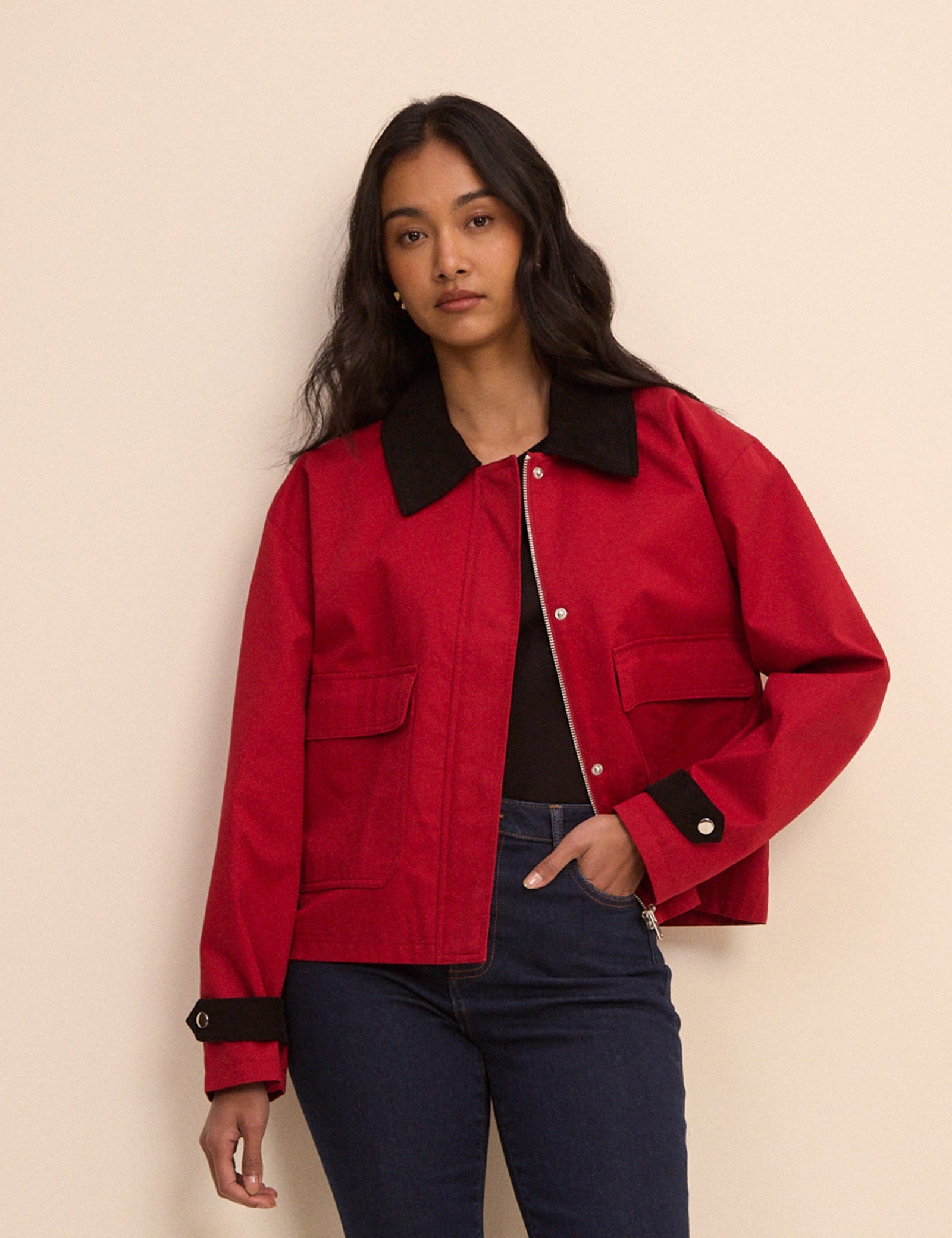 A cropped red barn jacket with contrasting black collar and cuffs.