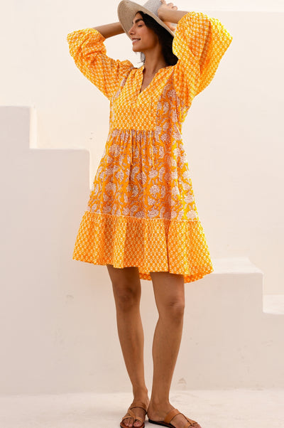 Woman wearing a yellow dress with a floral pattern on a white background