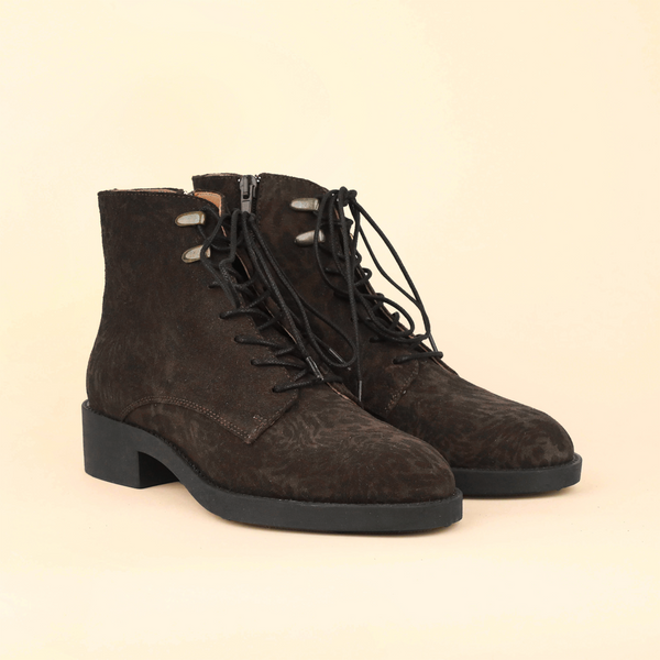 A pair of dark brown suede lace-up ankle boots with a low block heel, shown on a solid light beige background.