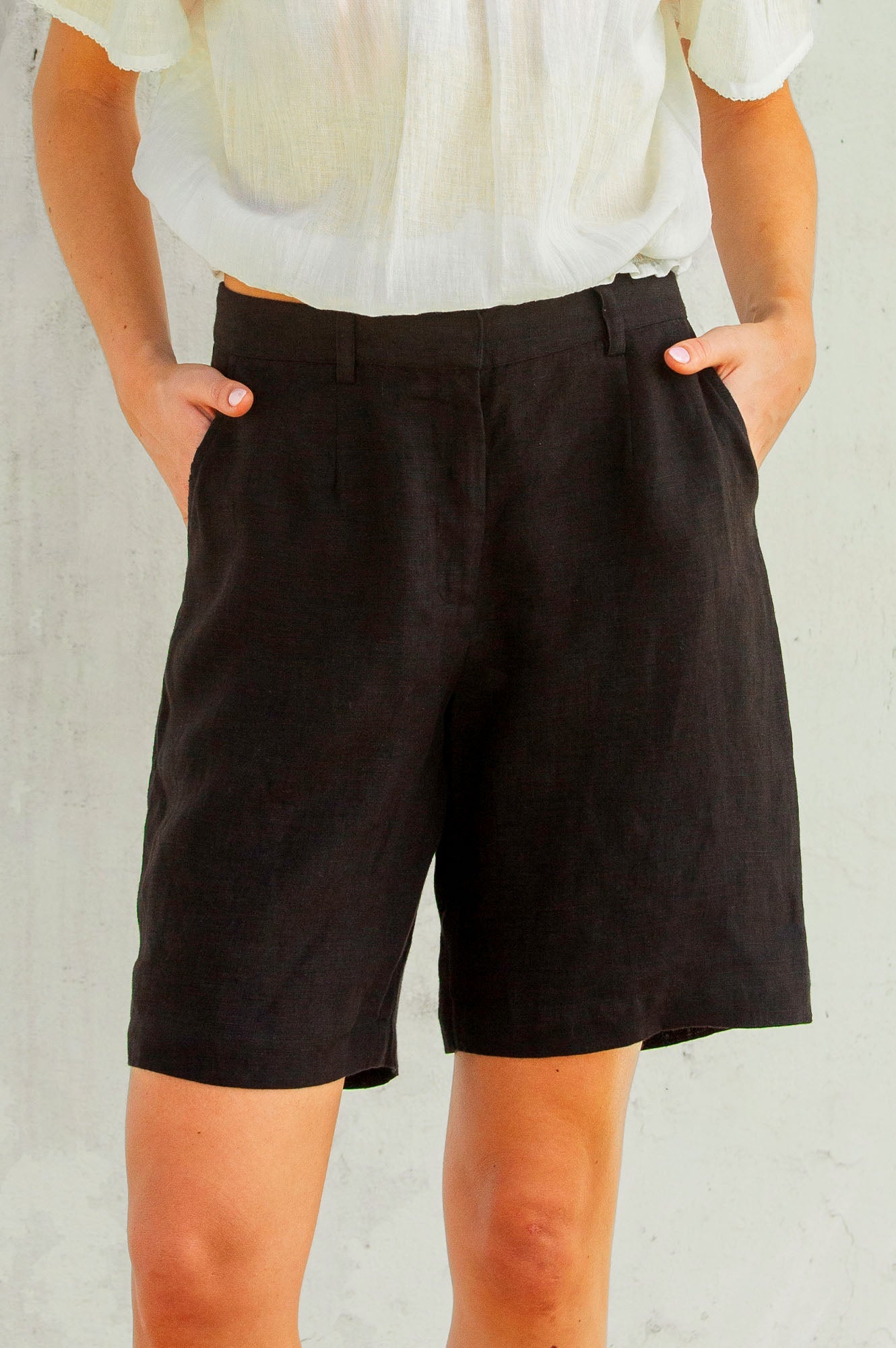 Black linen shorts with tailored waistband, side pockets, and relaxed fit.