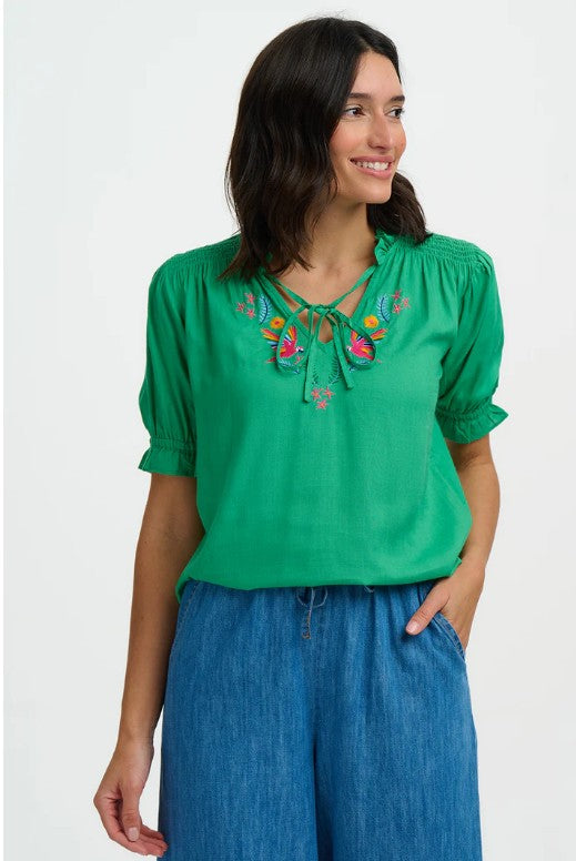 Emerald green blouse with bright parrot embroidery at tie neckline.