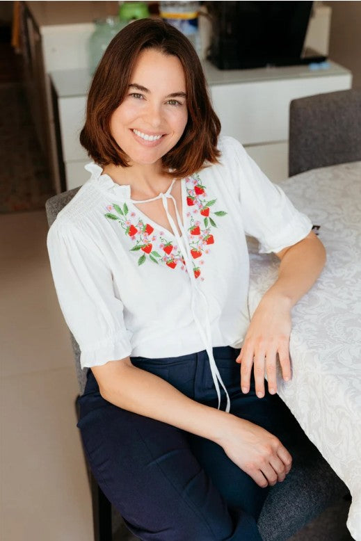 White shirred blouse with tie neck and red strawberry embroidery.