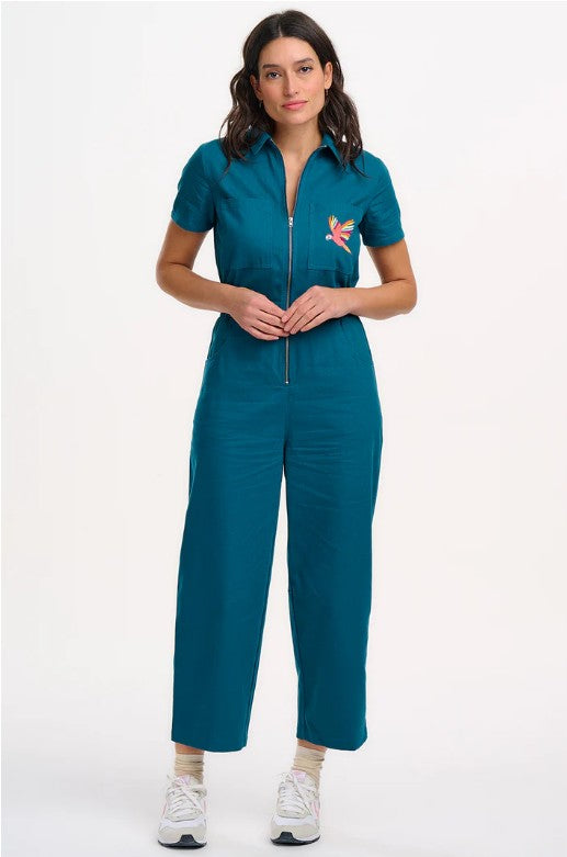 Teal organic cotton jumpsuit with embroidered parrot motif.