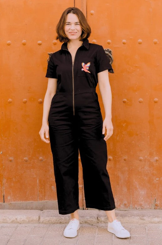 Black organic cotton jumpsuit with embroidered parrot motif.