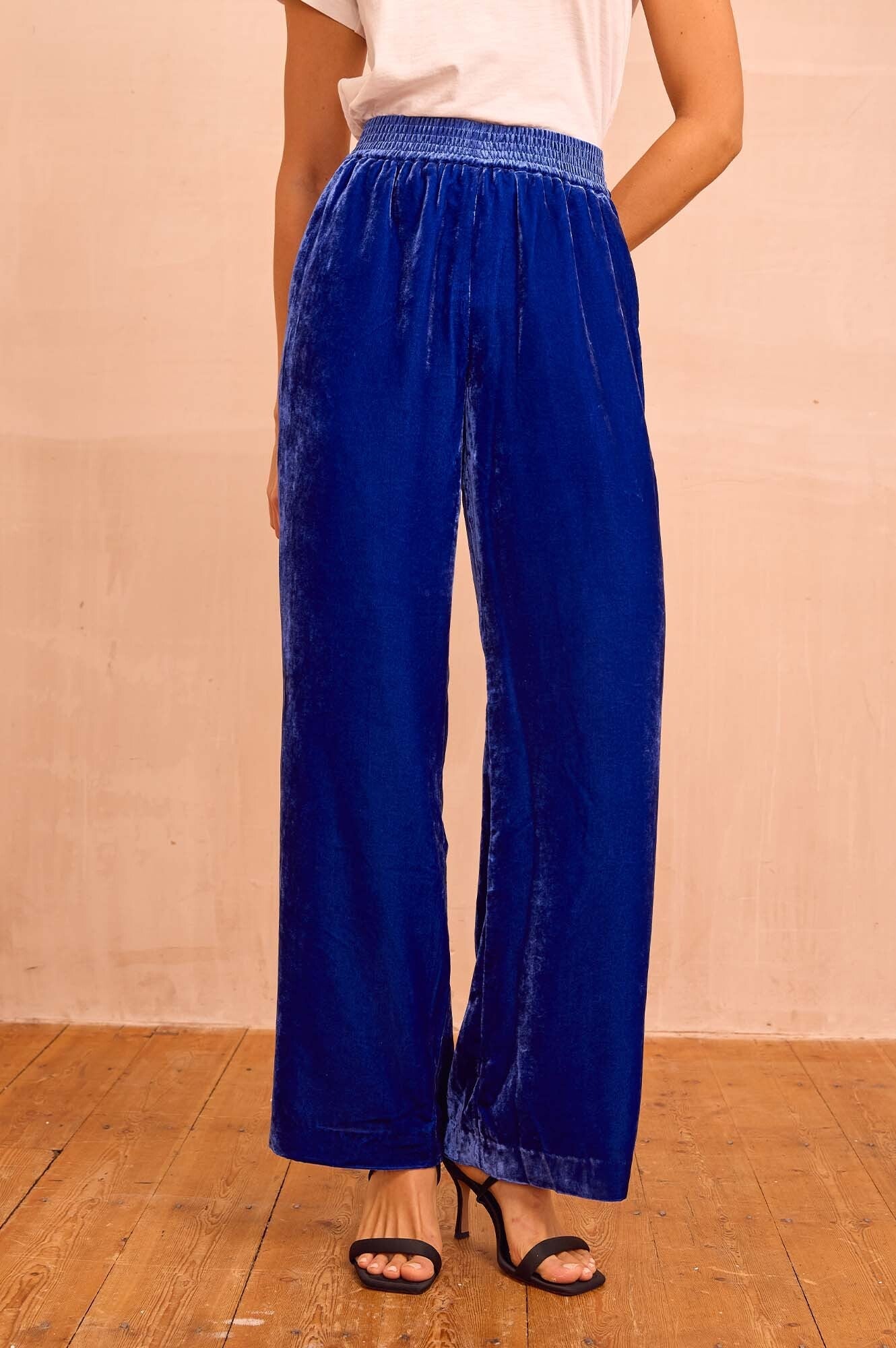 Cobalt blue velvet wide-leg trousers with elasticated waistband, relaxed fit, and full-length silhouette.