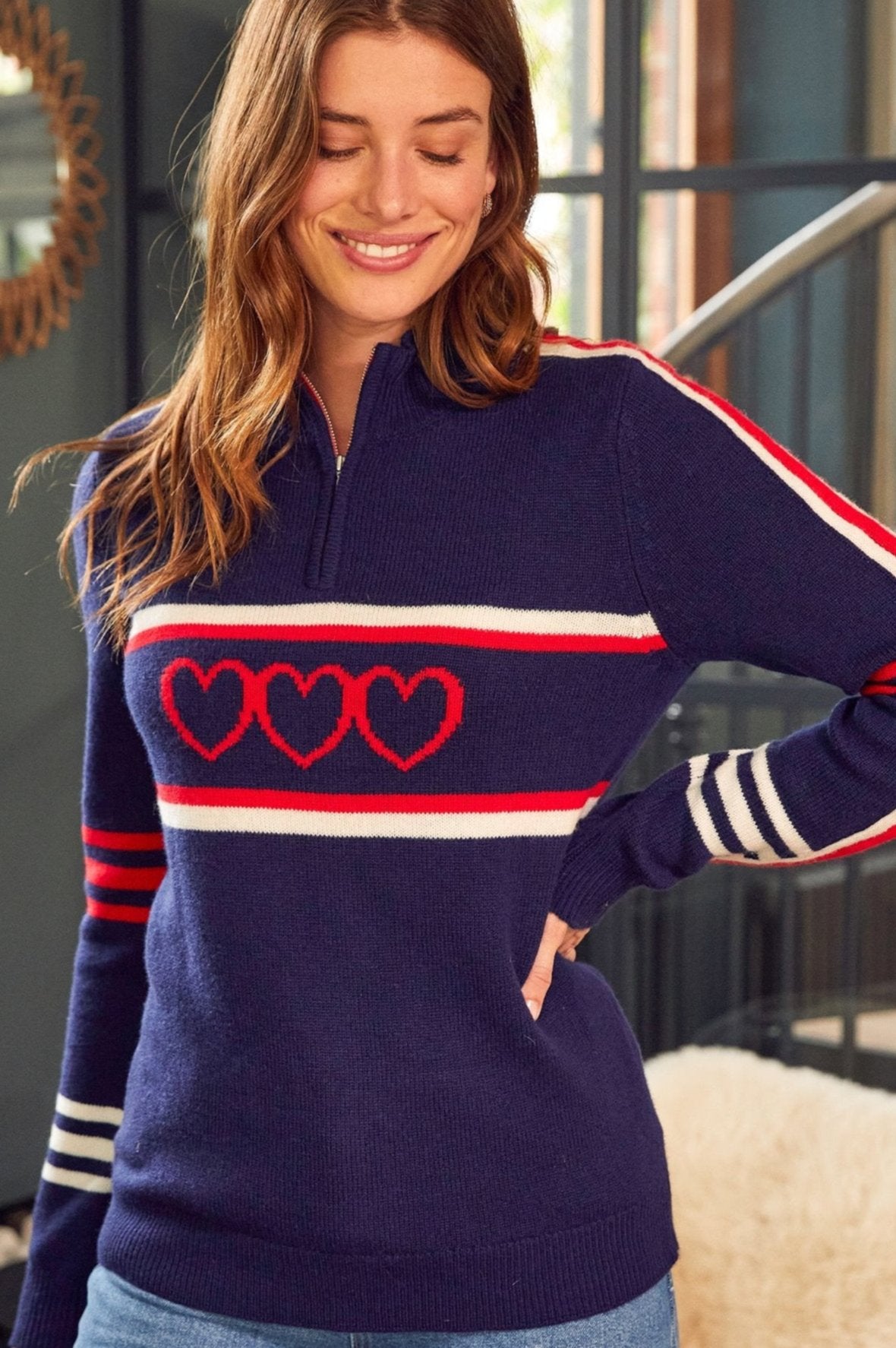 Navy knit merino sweater with half-zip neckline, red heart motif, and red and white stripe detailing.