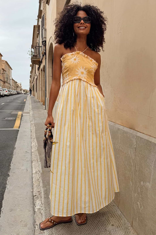 Yellow and white striped maxi dress with a fitted bodice, delicate floral detail at the neckline, and a flowing skirt.