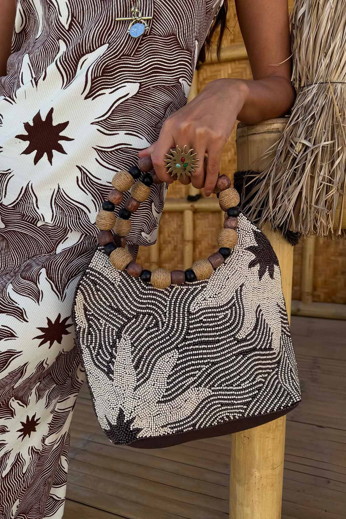 Small woven handbag in brown and cream with abstract pattern and rounded wooden bead handle.
