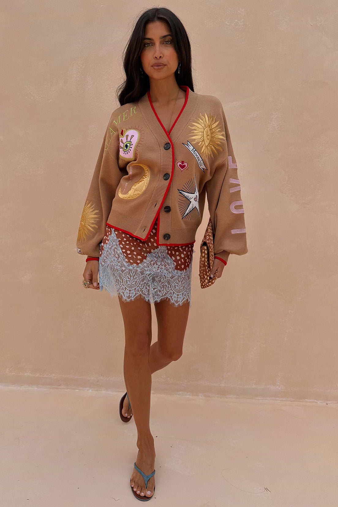 Camel coloured v-neck cardigan with red trim and sun and moon embroidery.