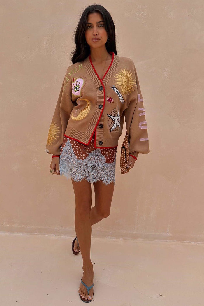 Camel coloured v-neck cardigan with red trim and sun and moon embroidery.