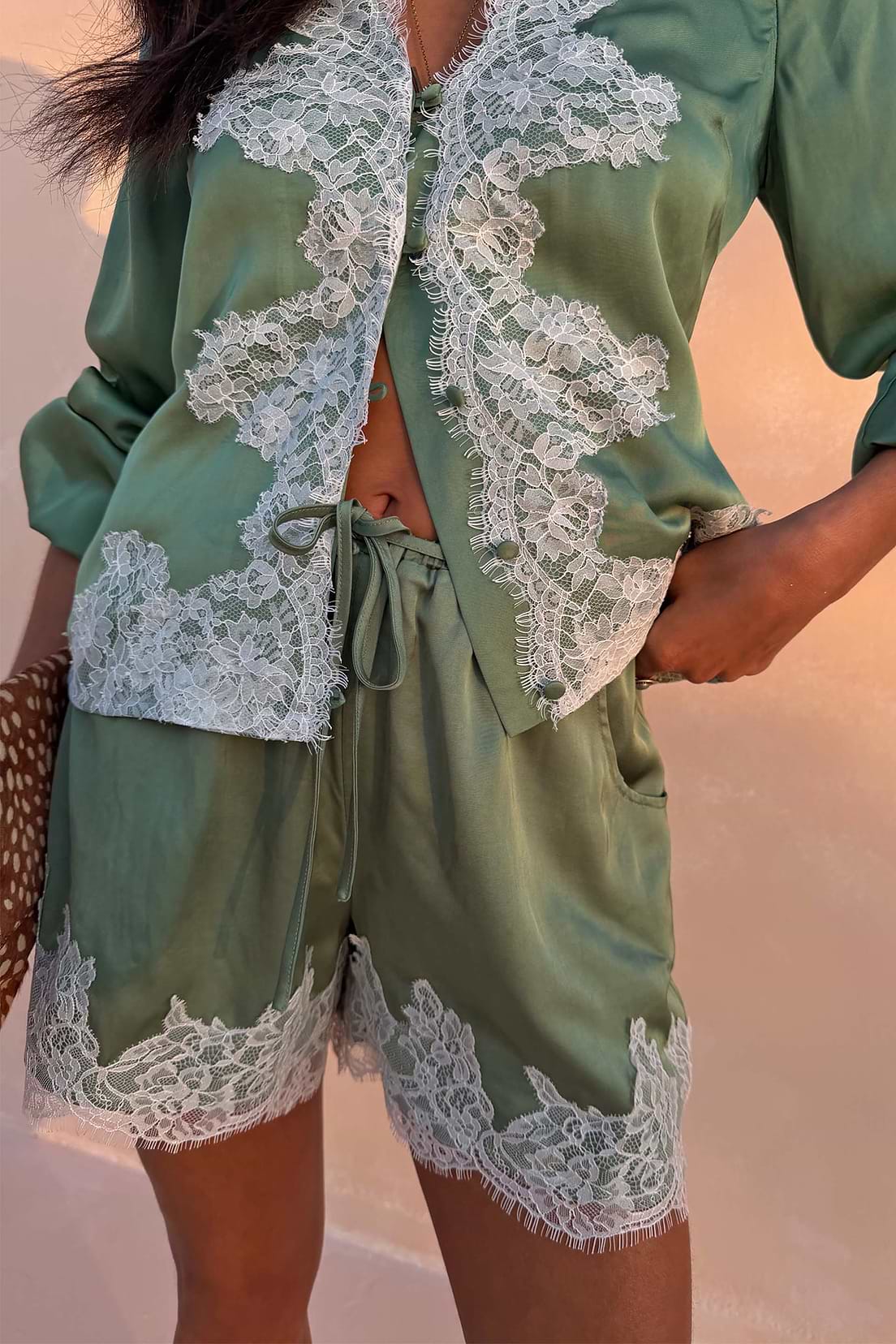 Sage green satin shorts with lace trim.