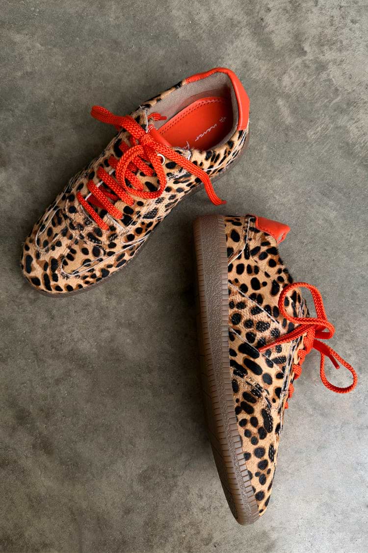 Leopard print trainers in tan and black with red-orange laces and trim, low-top silhouette and rubber sole