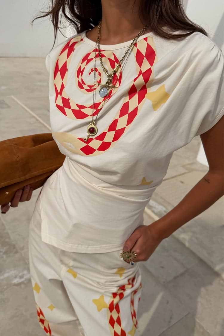 Cream short sleeve top with red geometric print and yellow star detailing, fitted silhouette