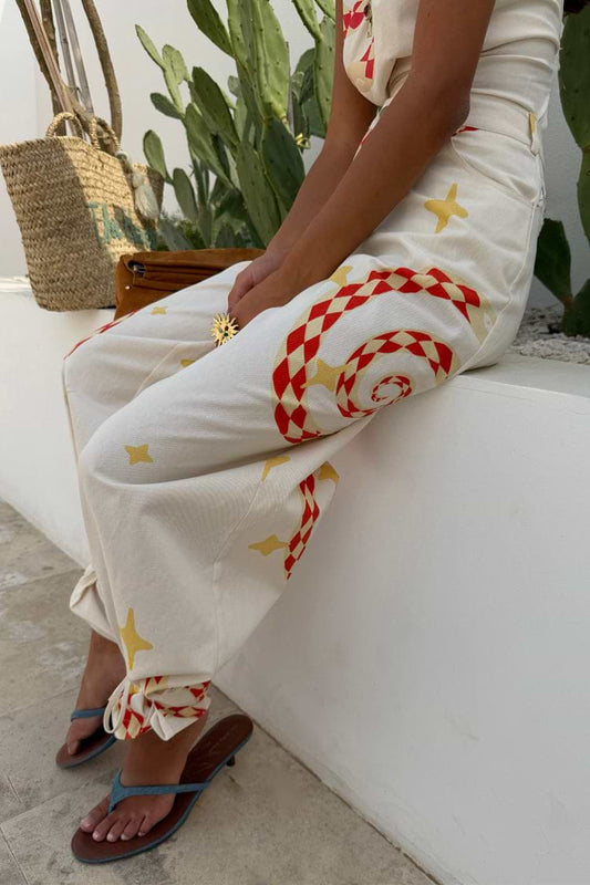 Cream trousers with red geometric print and yellow star detailing, relaxed fit with tapered ankle and soft drape