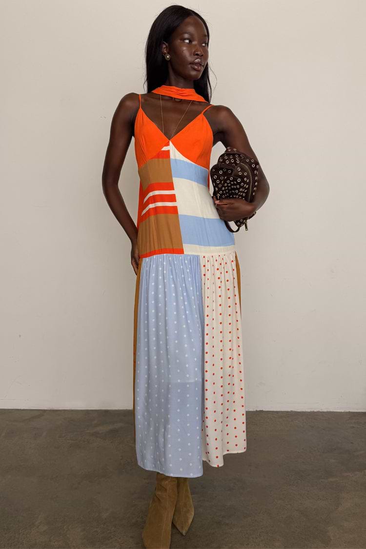 Multi-colour midi dress with red-orange bodice, tan and cream panels, light blue and cream skirt with mixed stripe and polka dot patterns, and sleeveless fitted silhouette