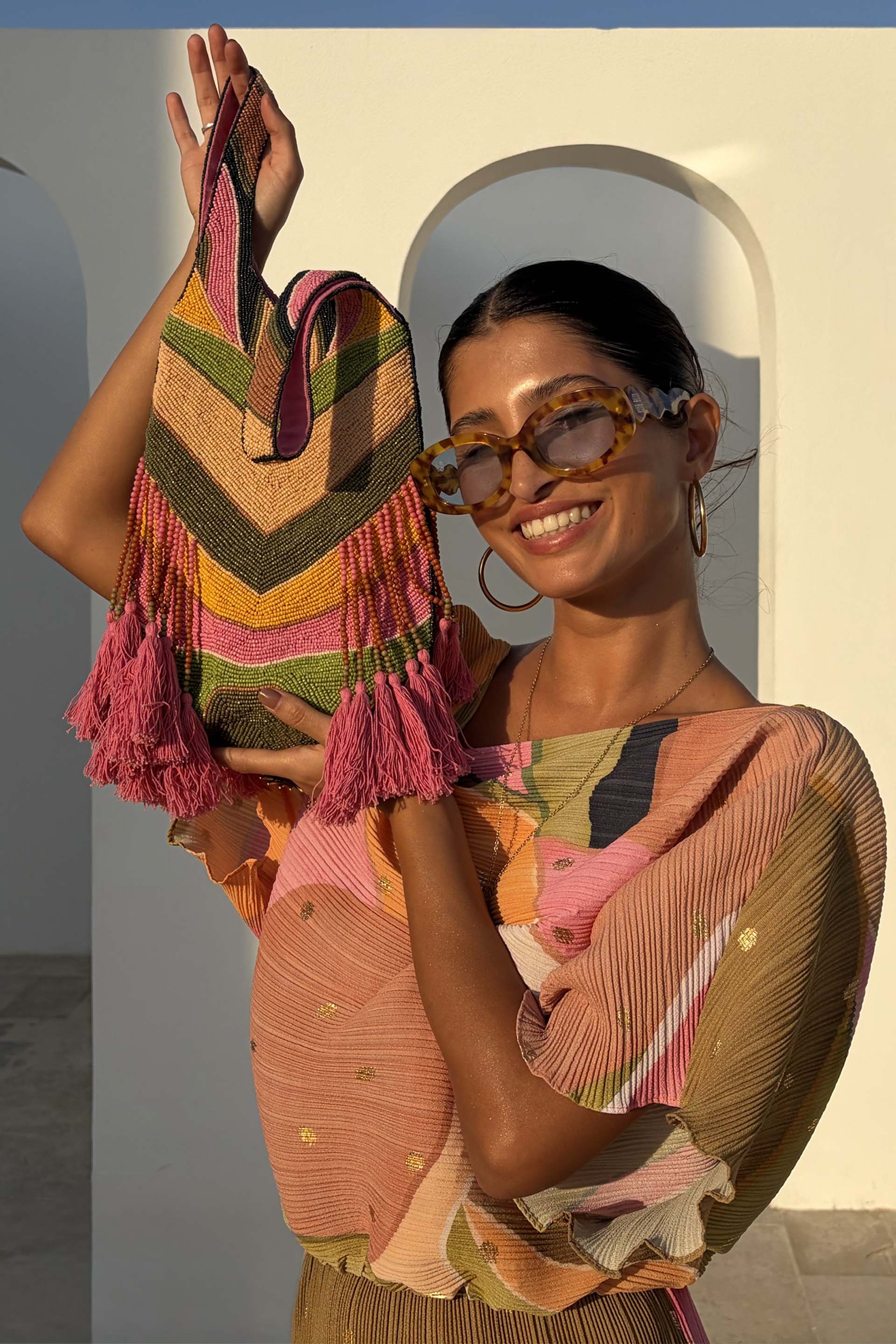 Chevron patterned woven bag in tan, olive, mustard, and pink with tassel detailing and structured top-handle silhouette