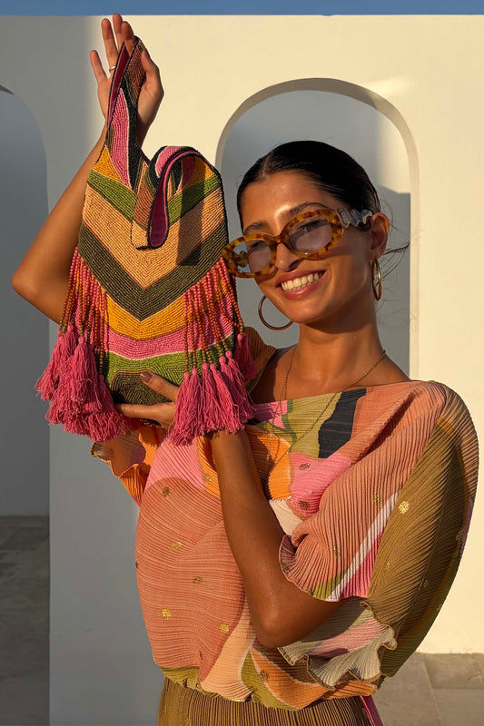 Chevron patterned woven bag in tan, olive, mustard, and pink with tassel detailing and structured top-handle silhouette