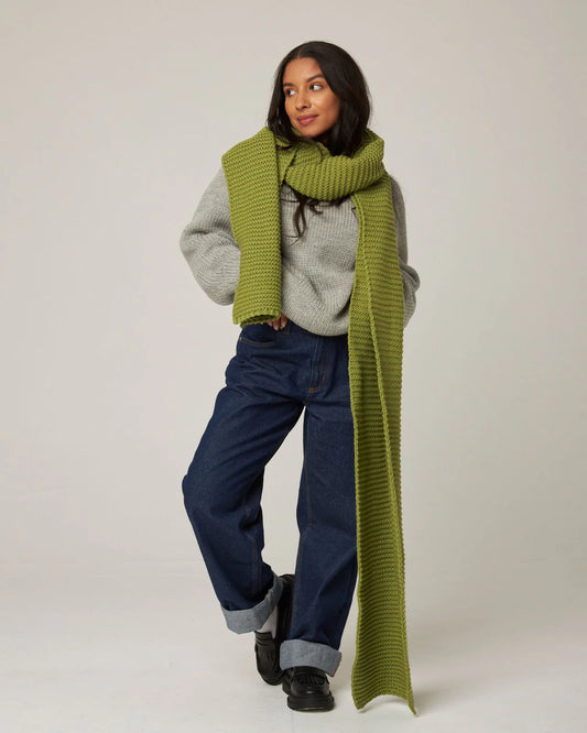 Model wears an oversized chunky knit moss green scarf, made from British merino wool by Peregrine Clothing. This scarf has been filtered by Shop My Palette for the Warm Spring, Warm Autumn, Clear Spring, and Light Spring colour seasons.