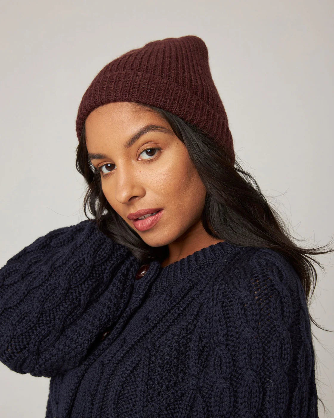 Model wears a deep, rich brown merino wool ribbed knit beanie hat by Peregrine Clothing, filtered for the Warm Spring, Clear Spring, Deep Autumn, and Warm Autumn colour seasons by Shop My Palette.