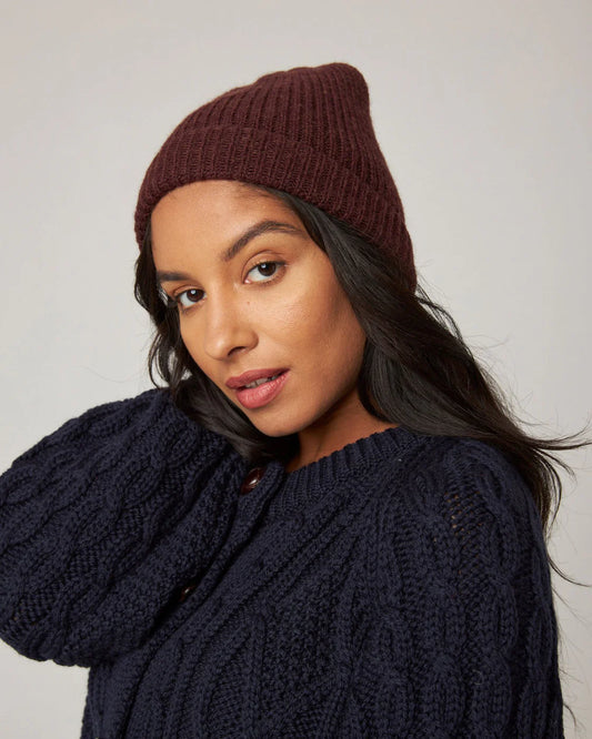 Model wears a deep, rich brown merino wool ribbed knit beanie hat by Peregrine Clothing, filtered for the Warm Spring, Clear Spring, Deep Autumn, and Warm Autumn colour seasons by Shop My Palette.