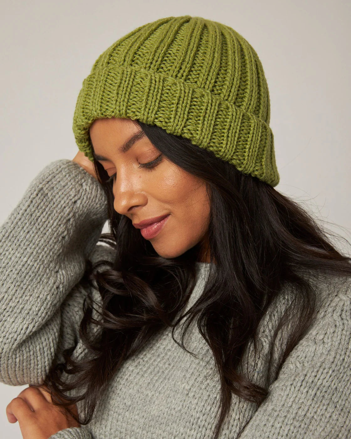 Model wears a moss green ribbed knitted merino wool beanie hat by Peregrine Clothing, filtered by Shop My Palette for the Warm Spring, Light Spring, Clear Spring, or Warm Autumn colour seasons.