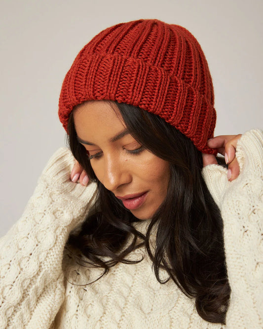 Model wears orange ribbed knit merino wool beanie hat by Peregrine Clothing, filtered for the Warm Autumn and Warm Spring colour seasons by Shop My Palette.