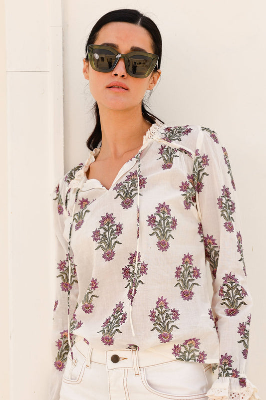 Cream floral block print blouse with ruffled neckline, long sleeves, and pink and green botanical pattern.