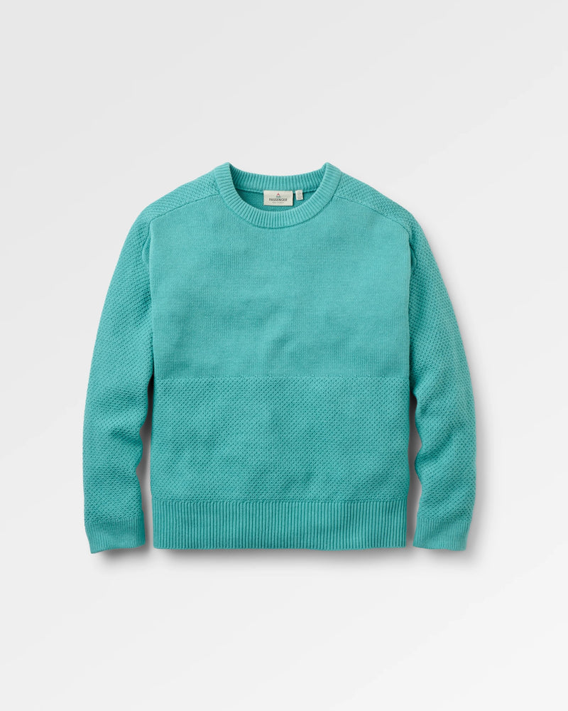 A turquoise knit crewneck sweater with a textured horizontal seam across the chest, displayed on a light grey background.