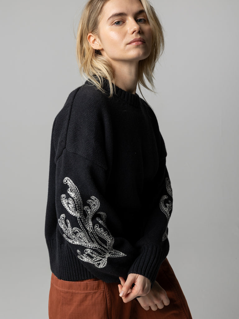 Charcoal organic cotton and wool jumper with white embroidery on sleeves.