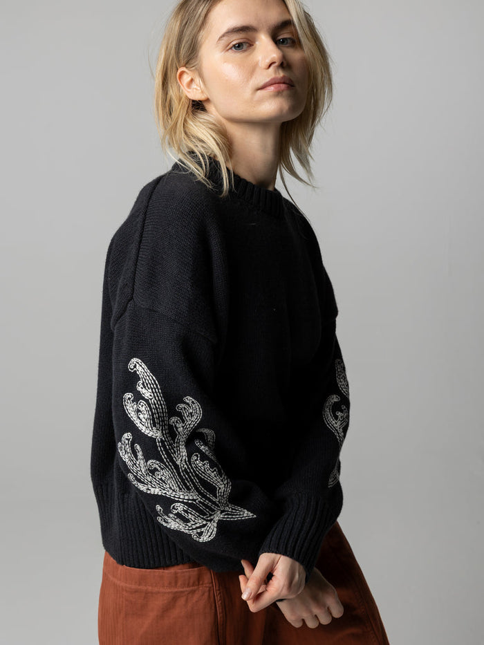 Charcoal organic cotton and wool jumper with white embroidery on sleeves.