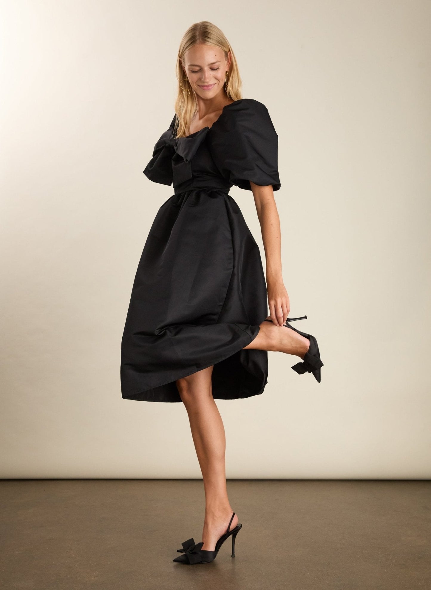 Black recycled polyester dress with puff sleeves and bow.
