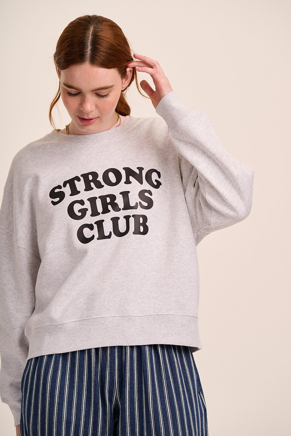 Light grey sweatshirt with ‘Strong Girls Club’ slogan, crew neckline, long sleeves, and relaxed fit.
