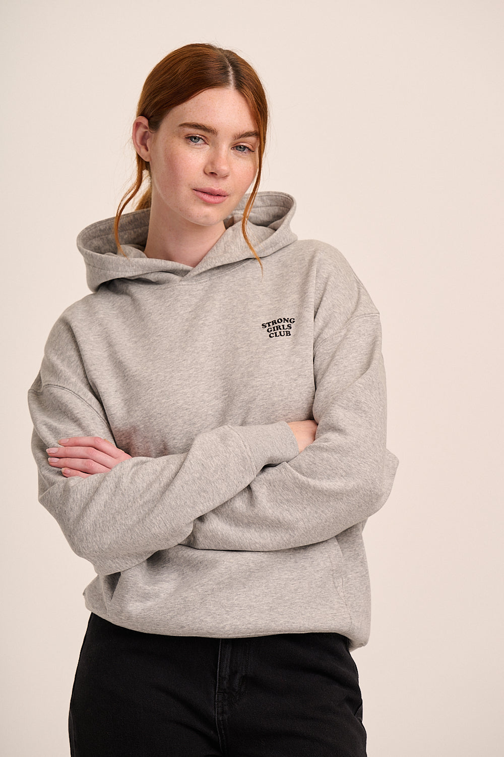 Light grey hooded sweatshirt with small ‘Strong Girls Club’ logo, long sleeves, and relaxed fit.