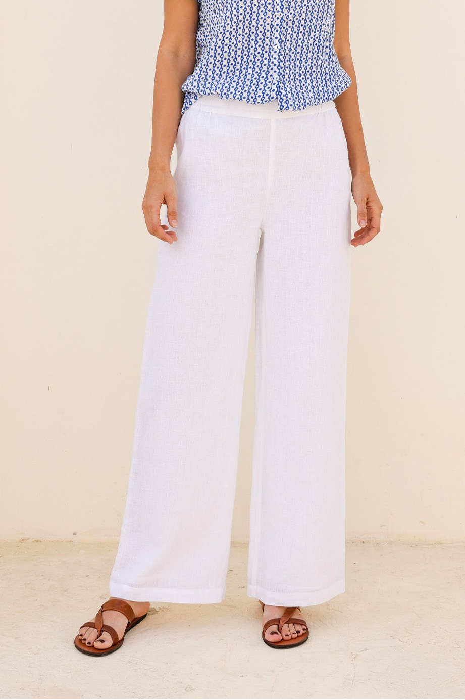 White wide-leg linen trousers with elasticated waistband and relaxed fit.